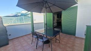 a table and chairs with an umbrella on a balcony at Vistagolf Maspalomas in Maspalomas