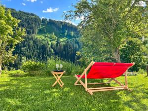 a red chair and a table with wine glasses at ALM SEASONS Premium Chalet & Studios in Saalbach-Hinterglemm