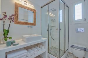 La salle de bains blanche est pourvue d'une douche et d'un lavabo. dans l'établissement Agapi's Houses, à Andiparos