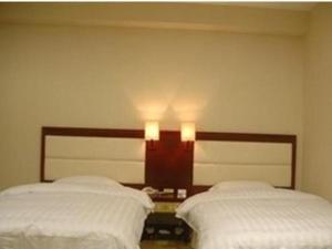 dwa łóżka w sypialni z dwoma światłami na ścianie w obiekcie Yidun Hotel Foshan Luocun w mieście Huanshi