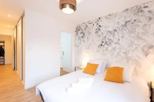 a bedroom with a white bed with two orange pillows at L'Escale Ocre - 150m Restaurant 3 étoiles - Climatisation in Vonnas