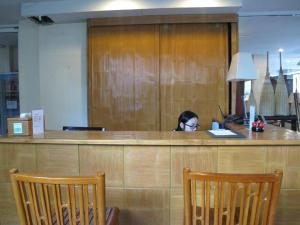 a woman sitting at a counter in a waiting room at Gerard Habitat Hotel in Chiang Mai