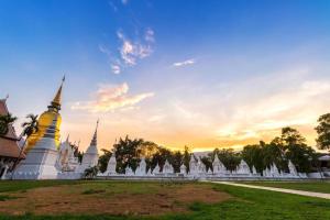 a temple with a sunset in the background at Gerard Habitat Hotel in Chiang Mai