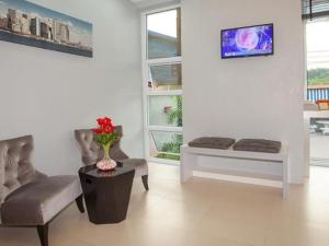 uma sala de estar com uma cadeira, uma mesa e janelas em Soontree House Hotel em Udon Thani