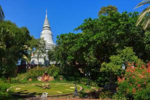 a garden with a pagoda in the background at Le President Hotel in Phnom Penh