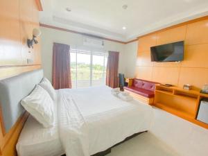 a bedroom with a white bed and a television at Siamtara Palace Hotel in Maha Sarakham