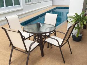 mesa, 2 sillas, mesa y piscina en The Grace Residence, en Surin