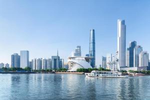 a boat in the water in front of a city at Wenxing Hotel Guangzhou Huajing Xincheng Branch in Guangzhou