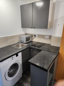 a kitchen with a washing machine and a microwave at OMLB DIRECT in Stanford-le-Hope