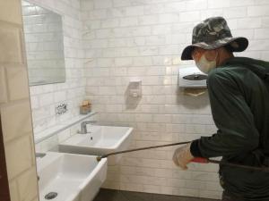 Um homem com um chapéu e uma máscara está a pintar um lavatório. em Malang Por Hotel em Ban Yuan
