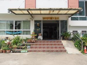 um edifício com escadas que levam a uma porta com plantas em Phetsuwan Hotel em Phetchabun