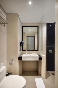 a bathroom with a sink and a mirror and a toilet at Fashion Hotel Legian in Legian