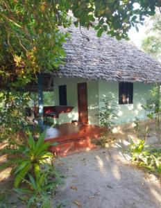 a small white house with a thatched roof at Mangrove Beach Bungalows in Utende