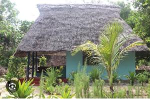 Cette petite maison bleue est dotée d'un toit de chaume. dans l'établissement Mangrove Beach Bungalows, à Utende