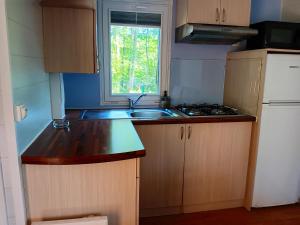 eine kleine Küche mit Spüle und Fenster in der Unterkunft Bungalow charmant avec piscine partagée à Saint-Chéron in Saint-Chéron