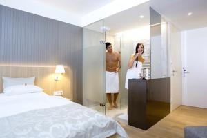 Ein Mann und eine Frau stehen in einem Spiegel in einem Schlafzimmer in der Unterkunft Thermenhotel Stoiser in Loipersdorf bei Fürstenfeld