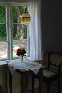 una mesa con un jarrón de flores y una ventana en Nästegården Bed & Breakfast, en Sätuna