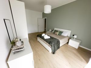 a white bedroom with a bed and wooden floors at Elegante & Moderno Loft in Centro Città in Seregno