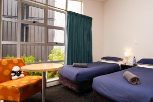 Habitación con 2 camas, mesa y silla en Haka Lodge Queenstown, en Queenstown
