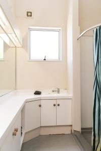 a white bathroom with a sink and a window at Haka Lodge Queenstown in Queenstown