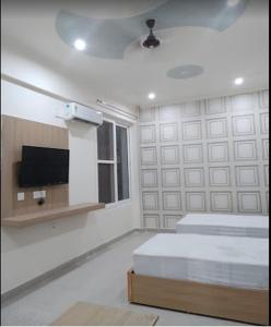 a bedroom with two beds and a tv on the wall at The Purezza in Greater Noida
