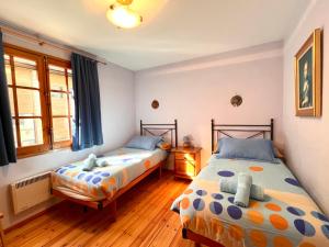 two beds in a bedroom with wooden floors and windows at Rústic de Llavorsí in Llavorsí