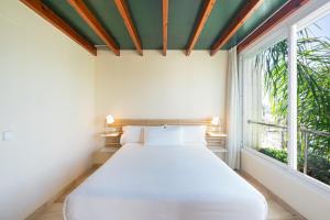 Cama blanca en habitación con ventana en MAREA ApartHotel, en Vilanova i la Geltrú