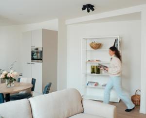 a woman walking in a living room with a book shelf at Urban Suites in Eindhoven