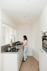 una mujer parada en una cocina preparando comida en Urban Suites, en Eindhoven