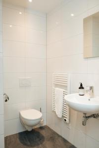 a white bathroom with a toilet and a sink at Urban Suites in Eindhoven