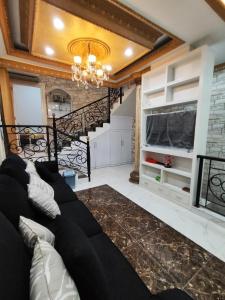 sala de estar con sofá negro y escalera en Rumah liburan 2 bedroom, 1 sofabed, 1 kitchen, en Yakarta
