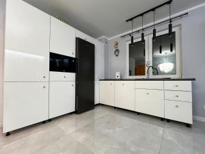 a kitchen with white cabinets and a sink at PaVoni Apartments Veranda Blu Mare in Łeba