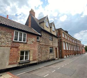un vieux bâtiment en briques situé sur le côté d'une rue dans l'établissement Spacious Grade II Listed Flint Cottage Sleeps 2, à Norwich