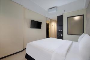 a bedroom with a white bed and a flat screen tv at Fashion Hotel Legian in Legian