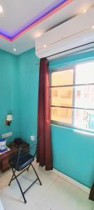 Hotel Ananya Inn في فاراناسي: غرفة زرقاء مع كرسي ونافذة