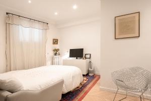 - une chambre blanche avec un lit et une chaise dans l'établissement Superb flat with terrasse & 24-7 security in the heart of Paris!, à Paris