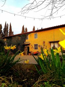 ein gelbes Haus mit gelben Blumen davor in der Unterkunft Podere Piandarca in Terranuova Bracciolini