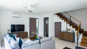 ein Wohnzimmer mit einem weißen Sofa und einem TV in der Unterkunft Laguna Park Villa in Phuket