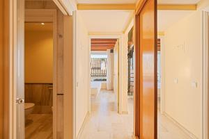 - un couloir menant à une salle de bains pourvue d'une baignoire dans l'établissement MAREA ApartHotel, à Vilanova i la Geltrú