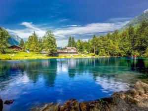 a lake in the mountains with a house in the background at Mountain Lodge *Nature *Queen Beds *Free parking in Oberwil