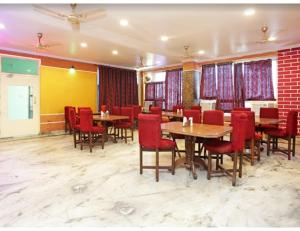 a restaurant with wooden tables and red chairs at Hotel Kamesh Hut, Varanasi in Varanasi
