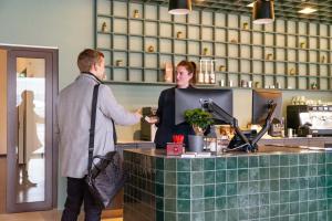 een man die een vrouw een glas wijn geeft bij Tailormade Hotel BAB Bachenbülach in Bachenbülach