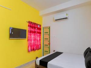 a bedroom with a bed and a tv on a yellow wall at OYO KVR RESIDENCY GRAND in Chennai
