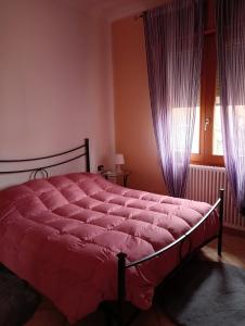a bed in a bedroom with purple curtains and a window at Home Sweet Home in Bologna