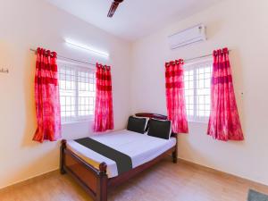 a small bedroom with red curtains and a bed at OYO KVR RESIDENCY GRAND in Chennai