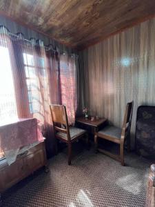 um quarto com duas cadeiras, uma mesa e uma janela em Flora Cottage , Srinagar em Srinagar