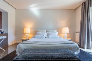 a bedroom with a large bed with two lamps at Kochab Comporta in Comporta