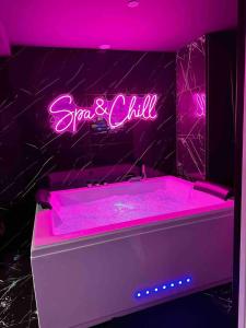 a pink neon sign sitting above a bath tub at Appartement d'une chambre avec sauna et wifi a Villeurbanne in Villeurbanne