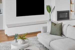 a living room with a couch and a tv on a wall at A Short time in Merimbula