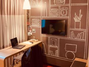 a desk with a laptop and a tv on a wall at ibis Toulouse Pont Jumeaux in Toulouse